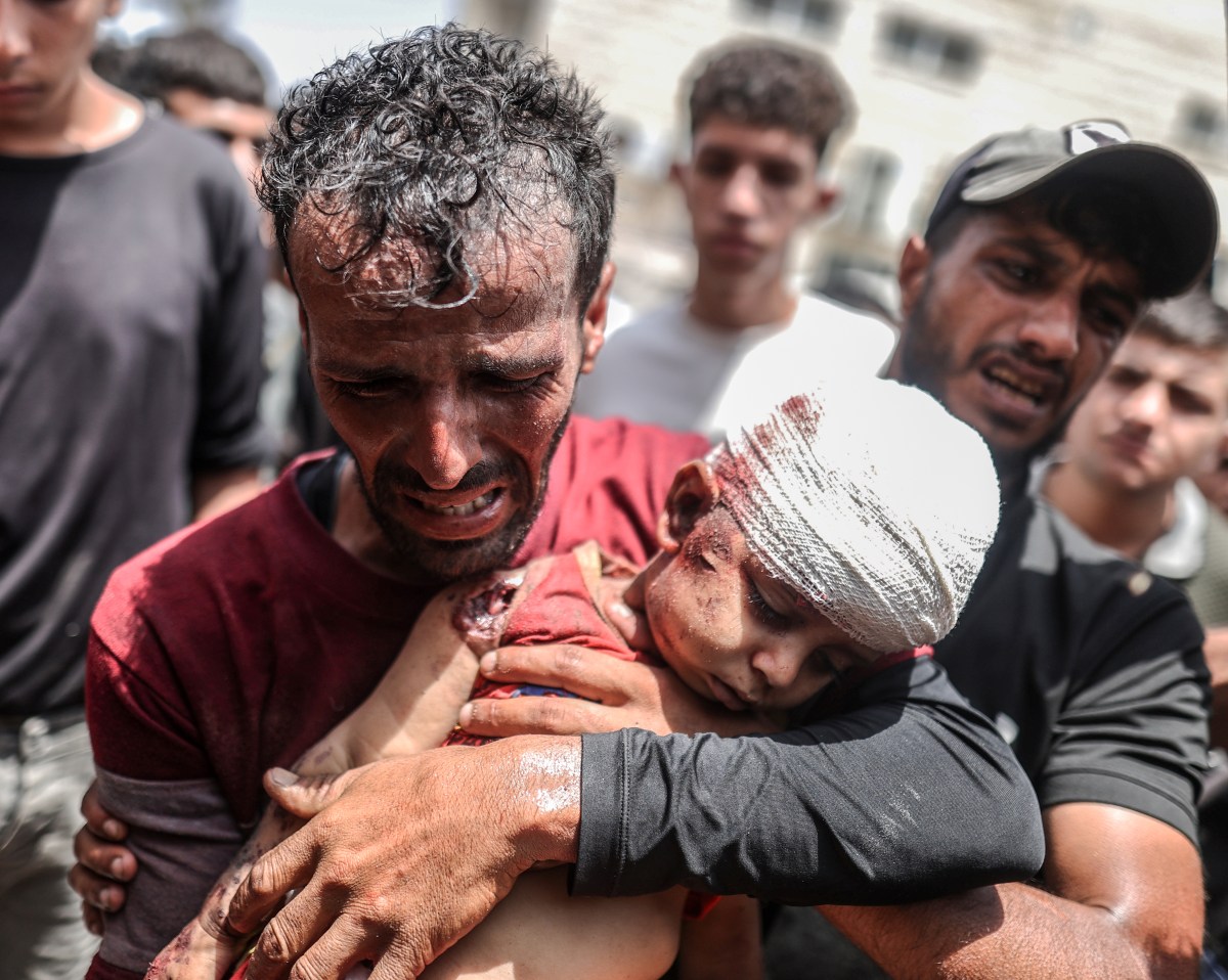 DEIR AL-BALAH, GAZA - JUNE 8: (EDITORS NOTE: Image depicts death) A man, holding a dead child, mourns as bodies of Palestinians, killed during simultaneous Israeli attacks on Nuseirat Refugee Camp, al-Bureij Refugee Camp and al-Maghazi Refugee Camp, are brought to Al-Aqsa Martyrs Hospital in Deir al-Balah, Gaza on June 8, 2024. It was reported that at least 40 Palestinians were killed. (Photo by Ali Jadallah/Anadolu via Getty Images)